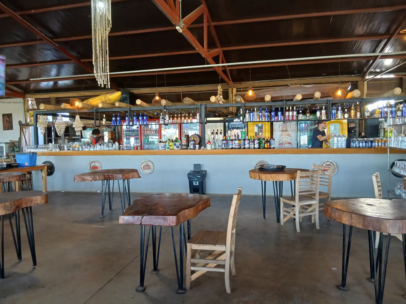 Balcão do bar com mesas de tronco de madeira
