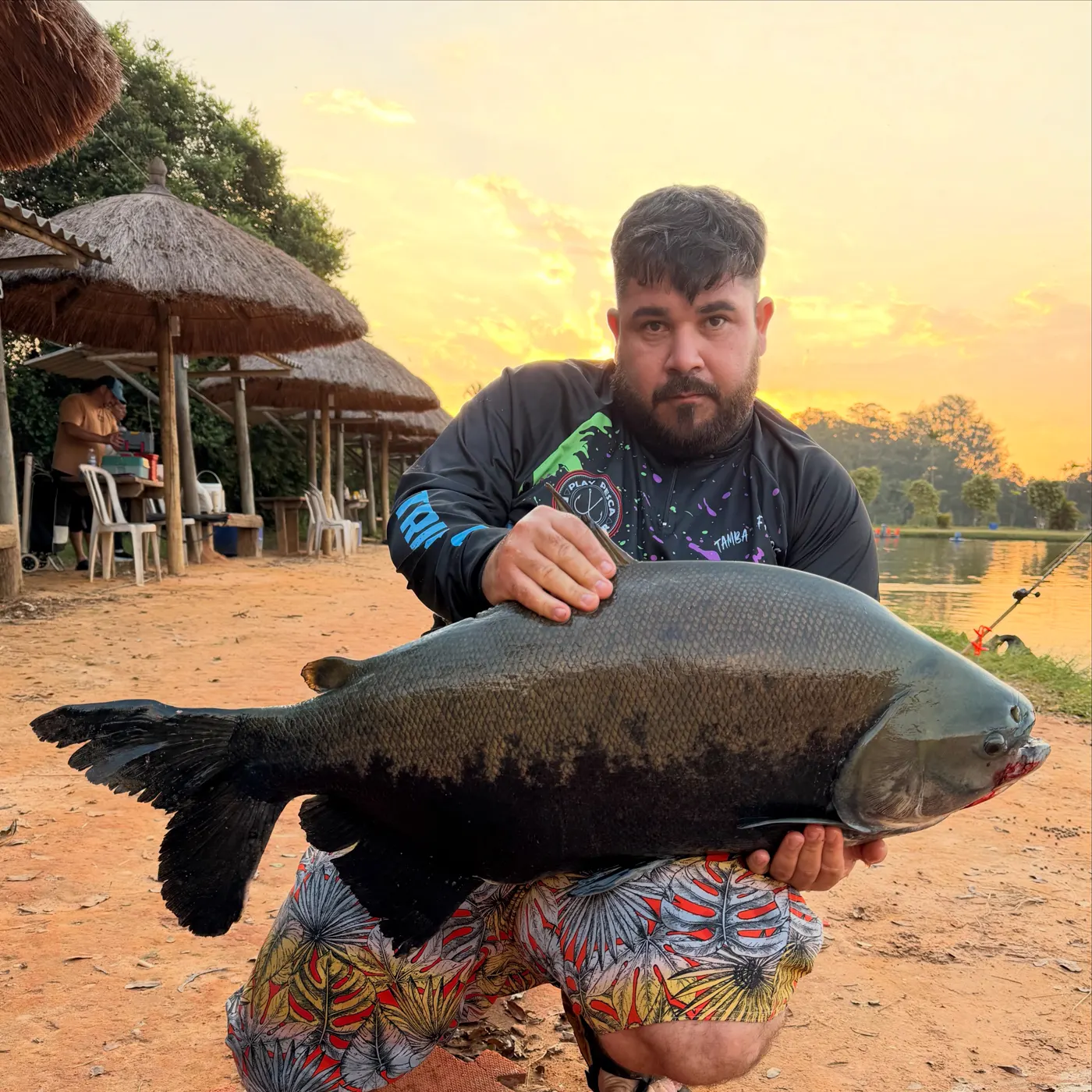 Pescador segurando um tambaqui ao entardecer