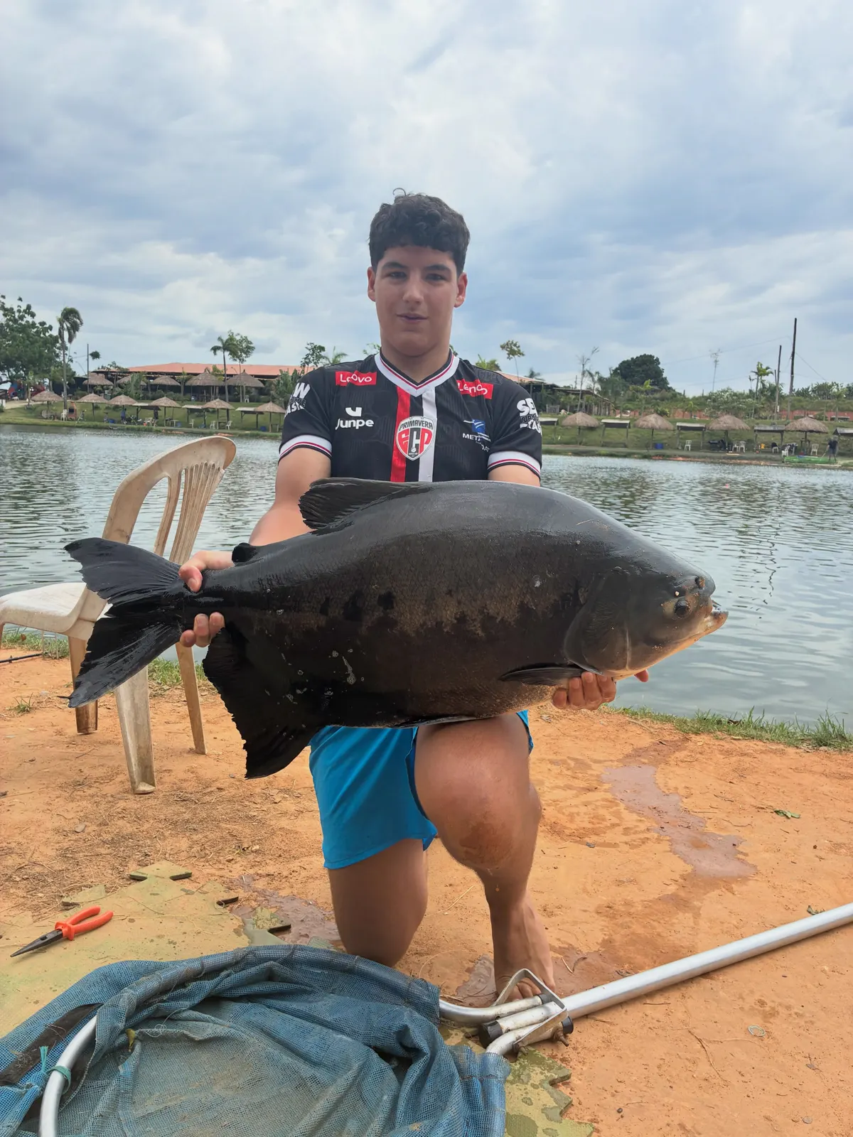 Jovem pescador segurando um tambaqui ao lado do puçá